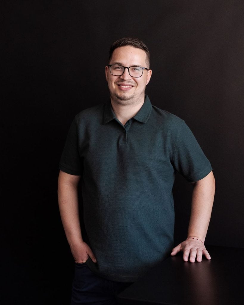 Dezvoltator software zâmbind, în fața unui fundal negru, pentru cursuri IT la Bytecode Academy România.